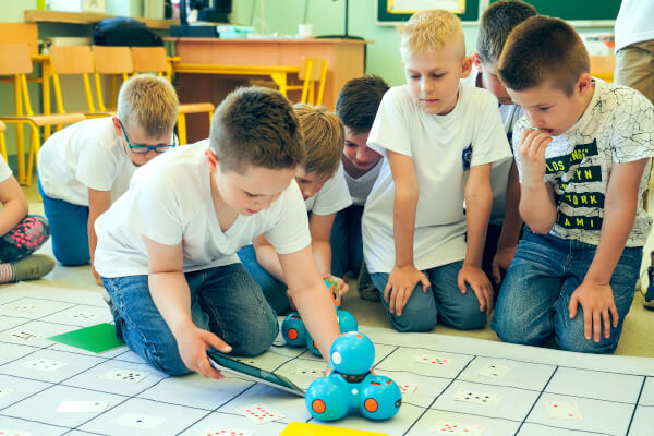 Zdjęcie przedstawia 8 dzieci które bawią się na macie zabawkowym robotem.